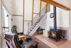 Living area with light wood finished floors, a high ceiling, and a wood stove