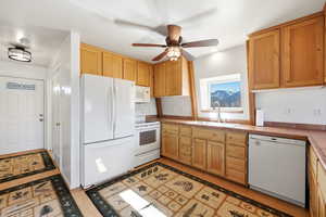 Kitchen with white appliances, tile countertops, ceiling fan, light wood-style flooring, and light wood finish cabinetry