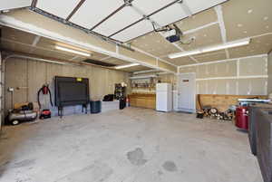 Garage with freestanding refrigerator and a garage door opener