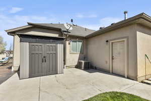 Back of house featuring stucco siding and a shed