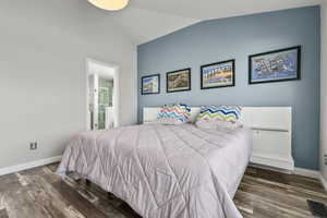 Bedroom featuring vaulted ceiling, dark wood-style floors, and connected bathroom