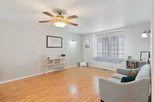 Living area with light wood finished floors and a ceiling fan