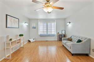 Sitting room with light wood-style floors and a ceiling fan
