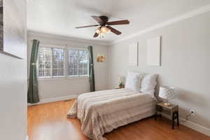 Bedroom with light wood finished floors, ornamental molding, and a ceiling fan