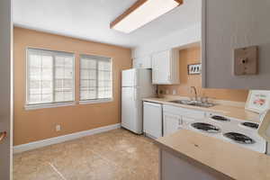Kitchen featuring white cabinets, light countertops, and white appliances