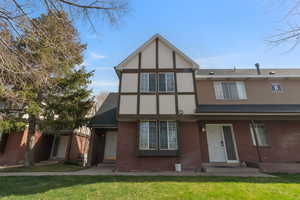 Tudor house featuring brick siding, roof with shingles, and a front lawn