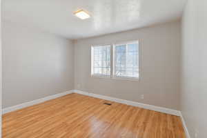 Empty room with light wood-style floors and a textured ceiling