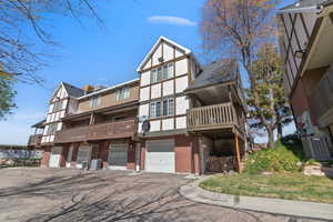 View of front of property with a balcony, brick siding, a garage, driveway, and stucco siding