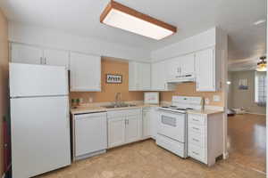 Kitchen with white appliances, light countertops, white cabinetry, and a ceiling fan