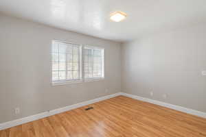 Unfurnished room with light wood finished floors and a textured ceiling