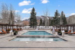Snow covered pool with a pergola, a community pool, and a patio