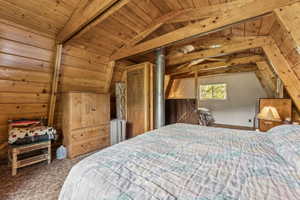 Bedroom with carpet floors and a wooden ceiling with exposed beams