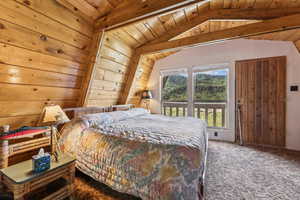 Carpeted bedroom featuring a wooden ceiling with exposed beams and wooden walls