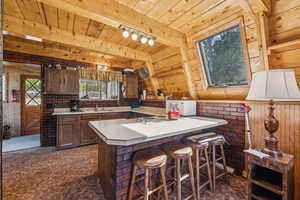 Kitchen with light countertops, white microwave, a peninsula, a breakfast bar area, and dark carpet