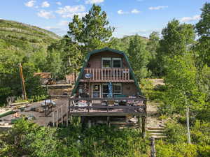Rear view of property with a gambrel roof, a deck with mountain view, and a view of trees