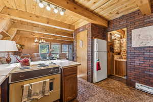 Kitchen featuring electric stove, freestanding refrigerator, suspended lighting, light countertops, and open floor plan
