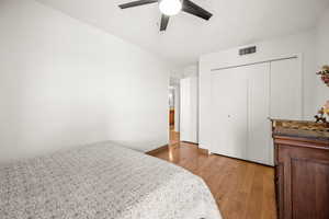 Bedroom with newer light wood finished floors, a large closet, and ceiling fan