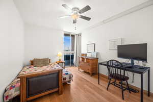 Second bedroom with light wood-style floors, ceiling fan and floor to ceiling windows