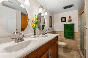 Full bathroom featuring double vanity, shower and tile floors