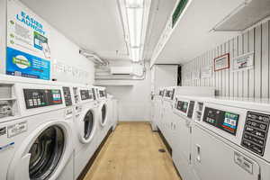 Community laundry room featuring a wall mounted mini split and washing machine and dryer