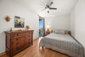 Bedroom featuring newer light wood finished floors, floor to ceiling window and a ceiling fan