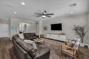 Living room with dark wood-style floors, a ceiling fan, and recessed lighting