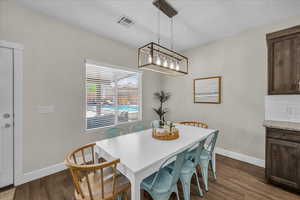 Dining area featuring dark wood-style flooring and baseboards