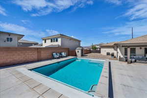 View of swimming pool with an outdoor hangout area, patio surround, a storage shed, and a fenced backyard