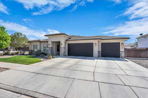 Prairie-style home featuring stucco siding, a tiled roof, a garage, driveway, and stone siding