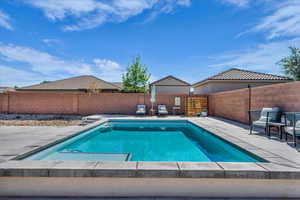 View of swimming pool with patio surround and a fenced backyard