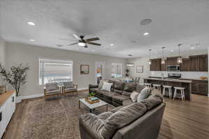 Living area with a textured ceiling, dark wood-style floors, recessed lighting, and ceiling fan