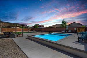 Pool at dusk featuring a patio area, outdoor lounge area, and a fenced backyard