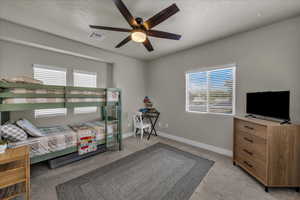 Bedroom featuring light colored carpet, a ceiling fan, and a textured ceiling