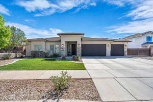Prairie-style home with stucco siding, a garage, stone siding, and a tiled roof