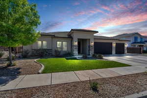 Prairie-style house featuring stone siding, an attached garage, a tiled roof, and stucco siding