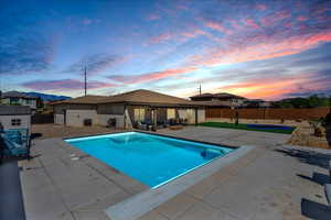 Pool at dusk with a patio and a fenced backyard