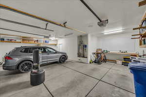 Garage with strapped water heater and a garage door opener