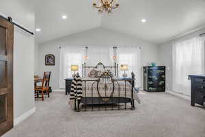Primary Bedroom with a barn door, light carpet, hanging lights, and multiple windows