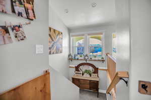 Hallway featuring lofted ceiling and baseboards