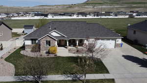 Craftsman-style home with stone siding, a front lawn, covered porch, concrete driveway, and a garage