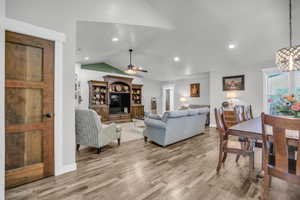 Living area featuring vaulted ceiling, light wood-style floors, a ceiling fan, and recessed lighting