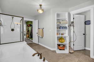Full primary bathroom with a shower stall, light tile patterned flooring, a bath, and a spacious closet