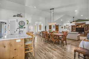 Dining area featuring a barn door, lofted ceiling, arched walkways, wood finished floors, and recessed lighting