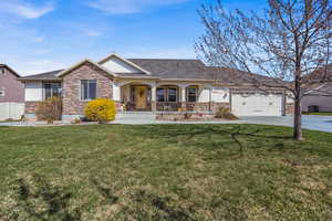 Craftsman-style home featuring a porch, stucco siding, a front yard, stone siding, and driveway