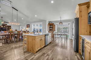 Kitchen with light wood finish cabinetry, light wood-style flooring, an island with sink, and stainless steel appliances