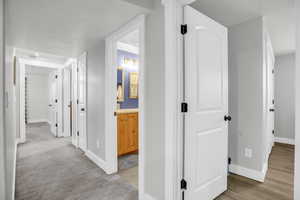 Corridor featuring baseboards and light colored carpet