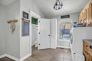 Laundry room with vaulted ceiling, light tile patterned floors, and washer and dryer