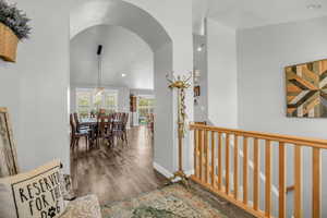 Hall with dark wood-style flooring, recessed lighting, and arched walkways