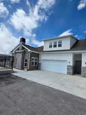 View of front of house featuring stone siding, stucco siding, concrete driveway, and a garage