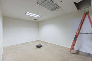 Unfurnished room with a drop ceiling and light carpet